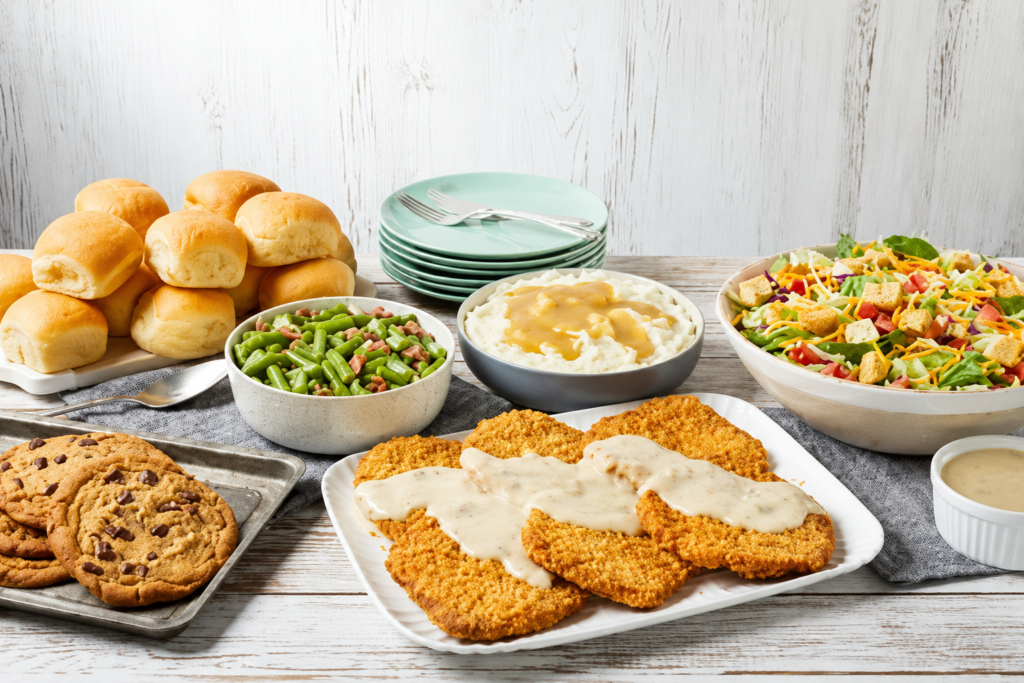 Comfort food family meal with fried cutlets, mashed potatoes, salad, rolls and cookies.