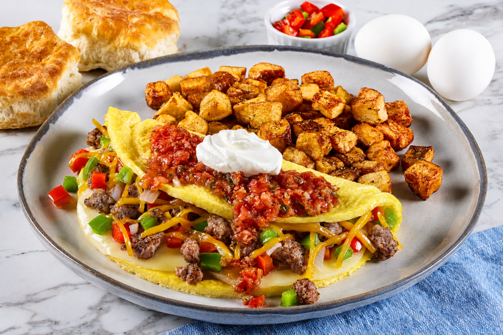 Omelets & Bowls, Loaded breakfast omelet filled with meat, peppers, onions and cheddar cheese, topped with salsa and sour cream, served with seasoned breakfast potatoes.