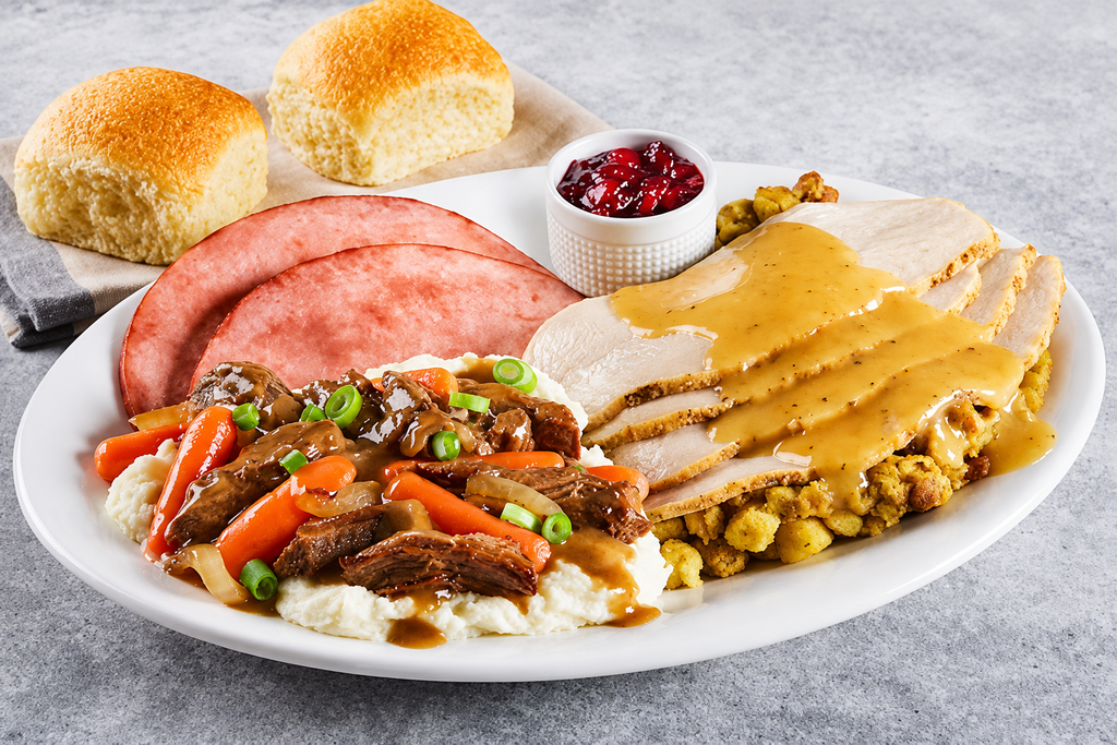 Taste of the Farm Trio with sliced turkey and gravy, ham steaks, pot roast with carrots and onions, mashed potatoes, dressing, cranberry sauce, and rolls.